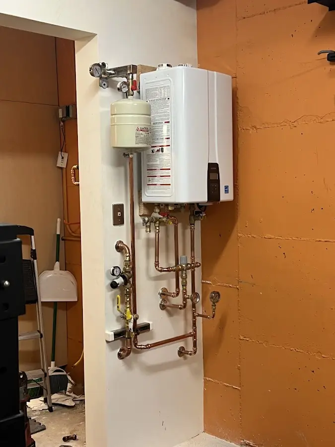 Plumbing technician inspecting water heater connections in Hounsfield